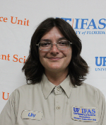 A woman with short brown hair smiles at the camera wearing a light blue collared shirt.